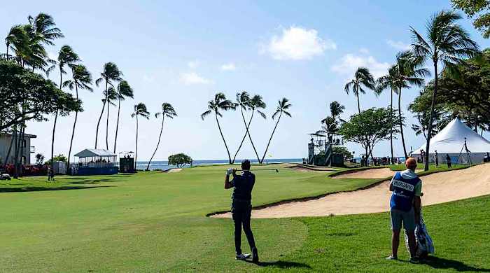 Mark Hubbard hits a shot with the iconic Waialae Country Club tree-form "W" in the background at the 2023 Sony Open in Hawaii.