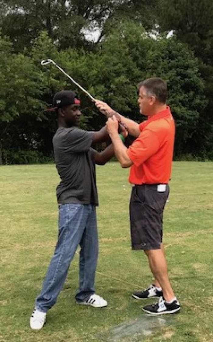 David Windsor, right, Georgia State Golf Association Director of Adaptive Golf, helps an autistic youth golfer learn the game's fundamentals. [Photo: xxxx]
