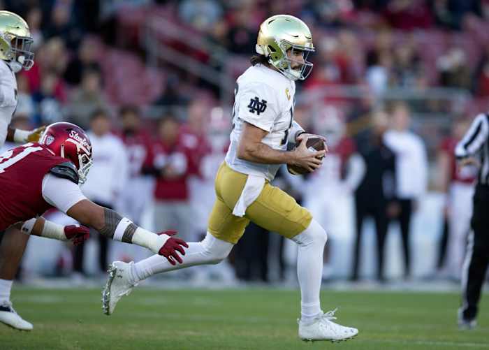 Nov 25, 2023; Stanford, California, USA; Notre Dame Fighting Irish quarterback Sam Hartman (10) scrambles away from pressure by Stanford Cardinal defensive lineman Jaxson Moi (51) during the first quarter at Stanford Stadium. Mandatory Credit: D. Ross Cameron-USA TODAY Sports