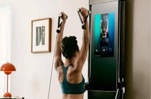 A woman using the Tonal smart home gym to exercise her shoulders