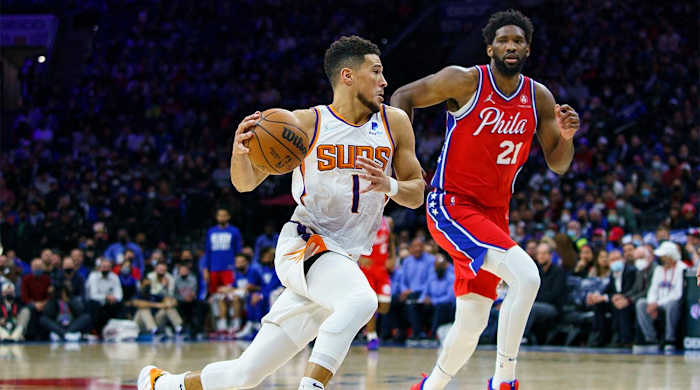 Phoenix Suns' Devin Booker, left, drives to the basket against Philadelphia 76ers' Joel Embiid, right, during the second half of an NBA basketball game, Tuesday, Feb. 8, 2022, in Philadelphia. The Suns won 114-109.