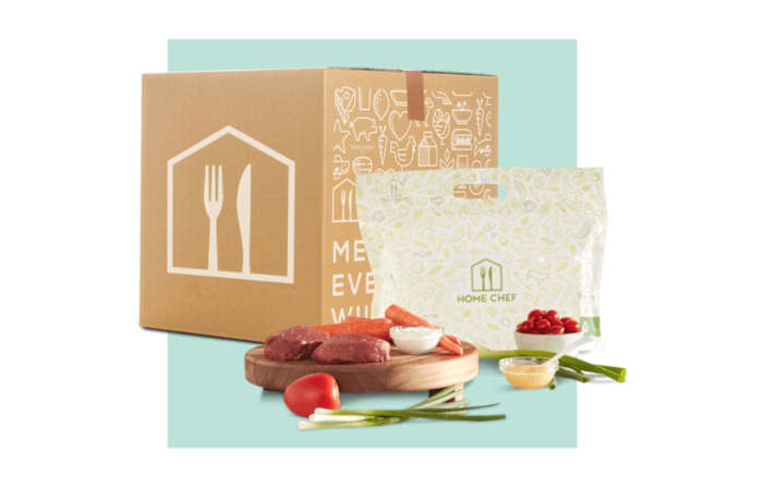 Meal kit ingredients on a cutting board next to a Home Chef branded cardboard box