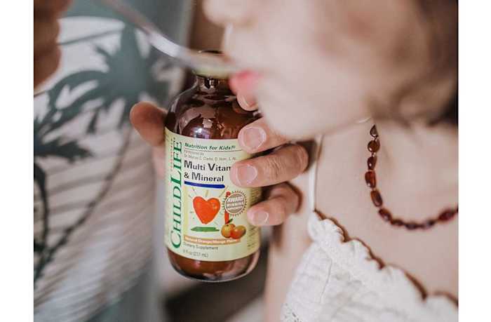 A child drinking a spoonful of ChildLife liquid multivitamin