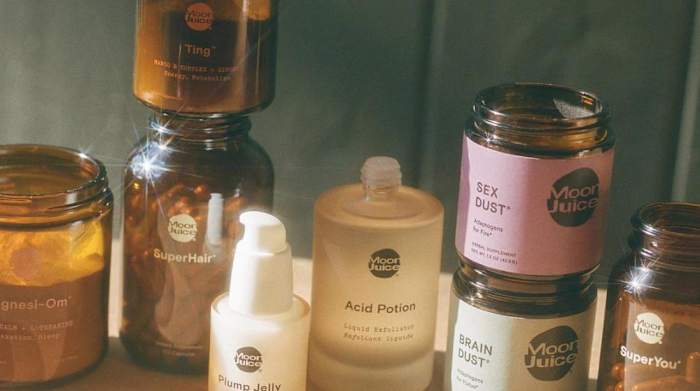 Several amber colored glass containers of Moon Juice products stacked on a table