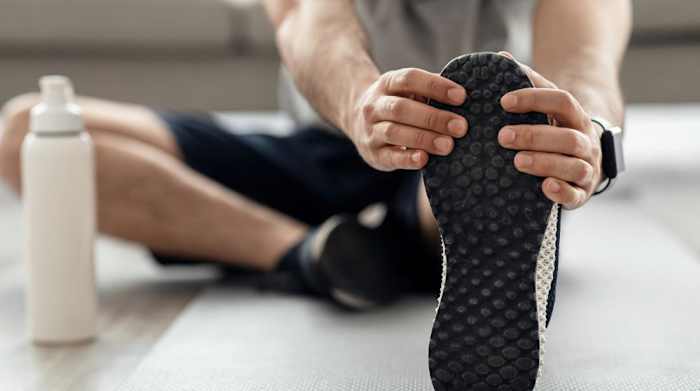 A man sitting on the floor stretching his hamstrings