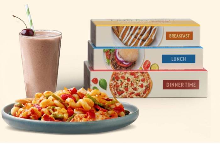 Plate of pasta next to chocolate cherry milkshake and three boxed meals