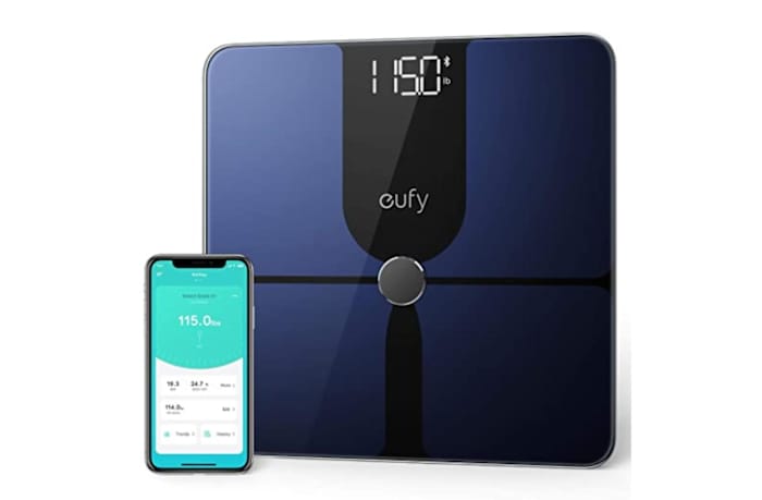 The Eufy P1 bathroom scale in navy blue and black next to a smartphone opened to the Eufy app
