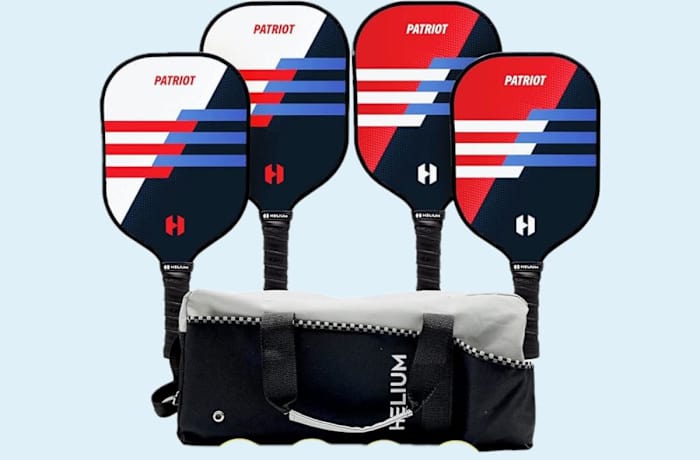 Four Helium Versus Pickleball Paddles all with black handles and a red, white and blue hitting surface next to a blue and white Helium storage bag.