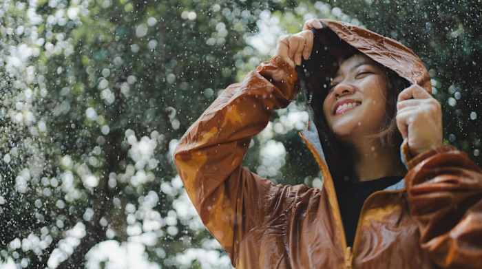 A woman wearing an orange rain jacket in the rain.