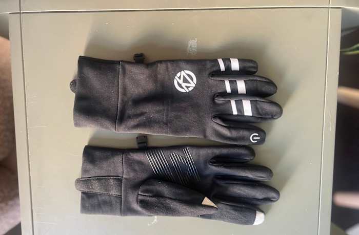 A tester's pair of Zensah Smart running gloves against a beige background