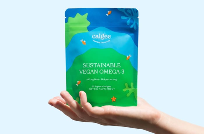 A person holding a blue and green bag of Calgee Sustainable Vegan Omega-3 softgels