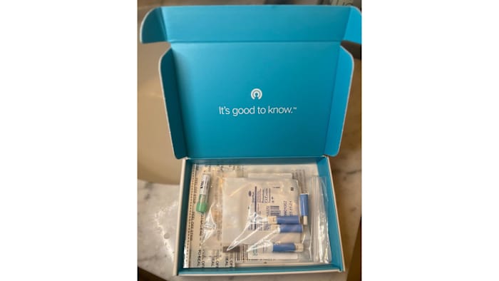 Components of the LetsGetChecked Thyroid test kit packaged in a turquoise and white delivery box.