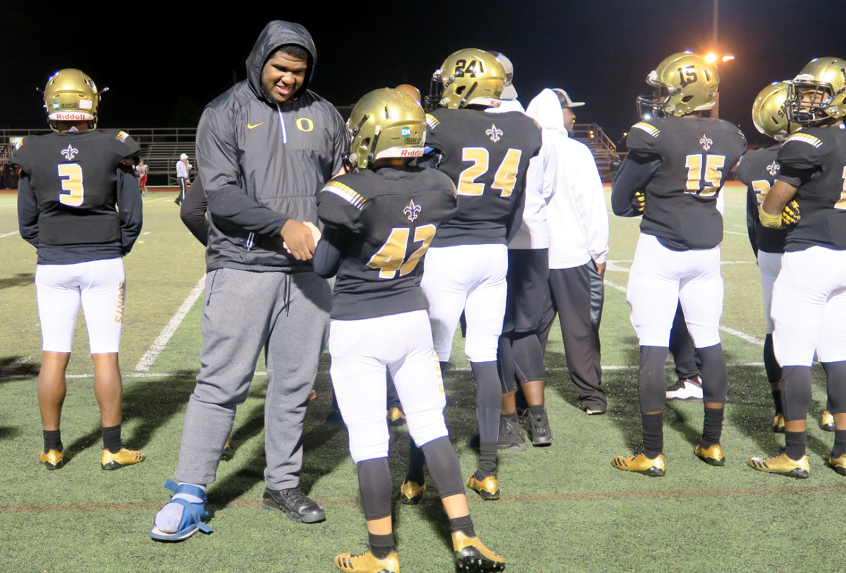 Justin Johnson (in boot), who’s committed to Oregon, gives pointers on the sideline to a teammate.