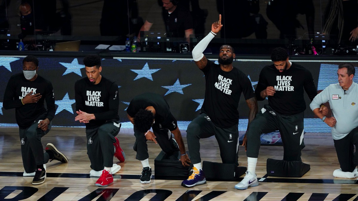 Los Angeles Lakers' LeBron James (23) points upwards while kneeling with teammates prior to facing the Denver Nuggets in the first half of an NBA basketball game Monday, Aug. 10, 2020, in Lake Buena Vista.