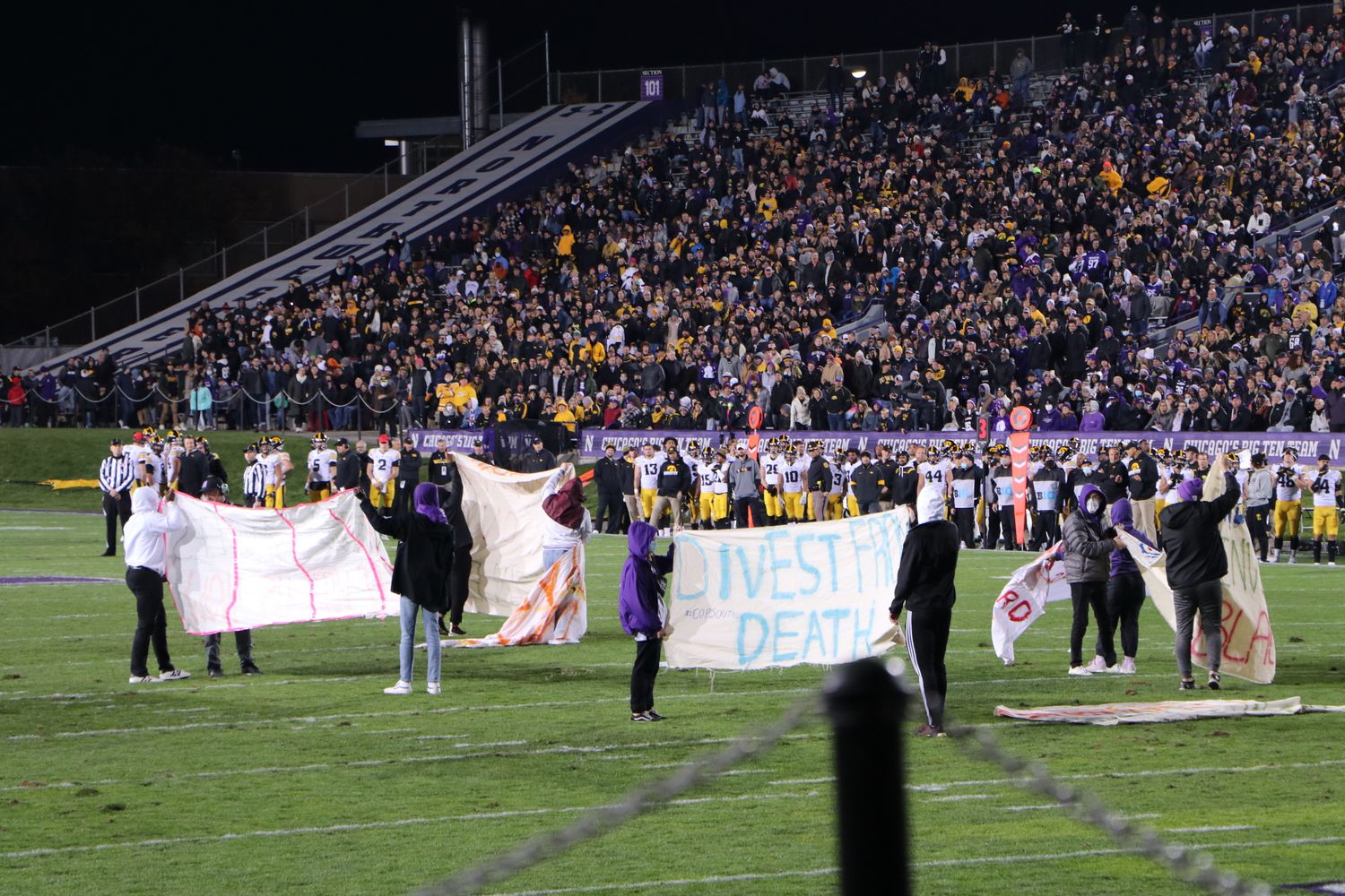 Nine protesters took the field to display handmade signs during the first half of Northwestern vs. Iowa on Saturday, Nov. 6, 2021. (Photo by Lauren Withrow)
