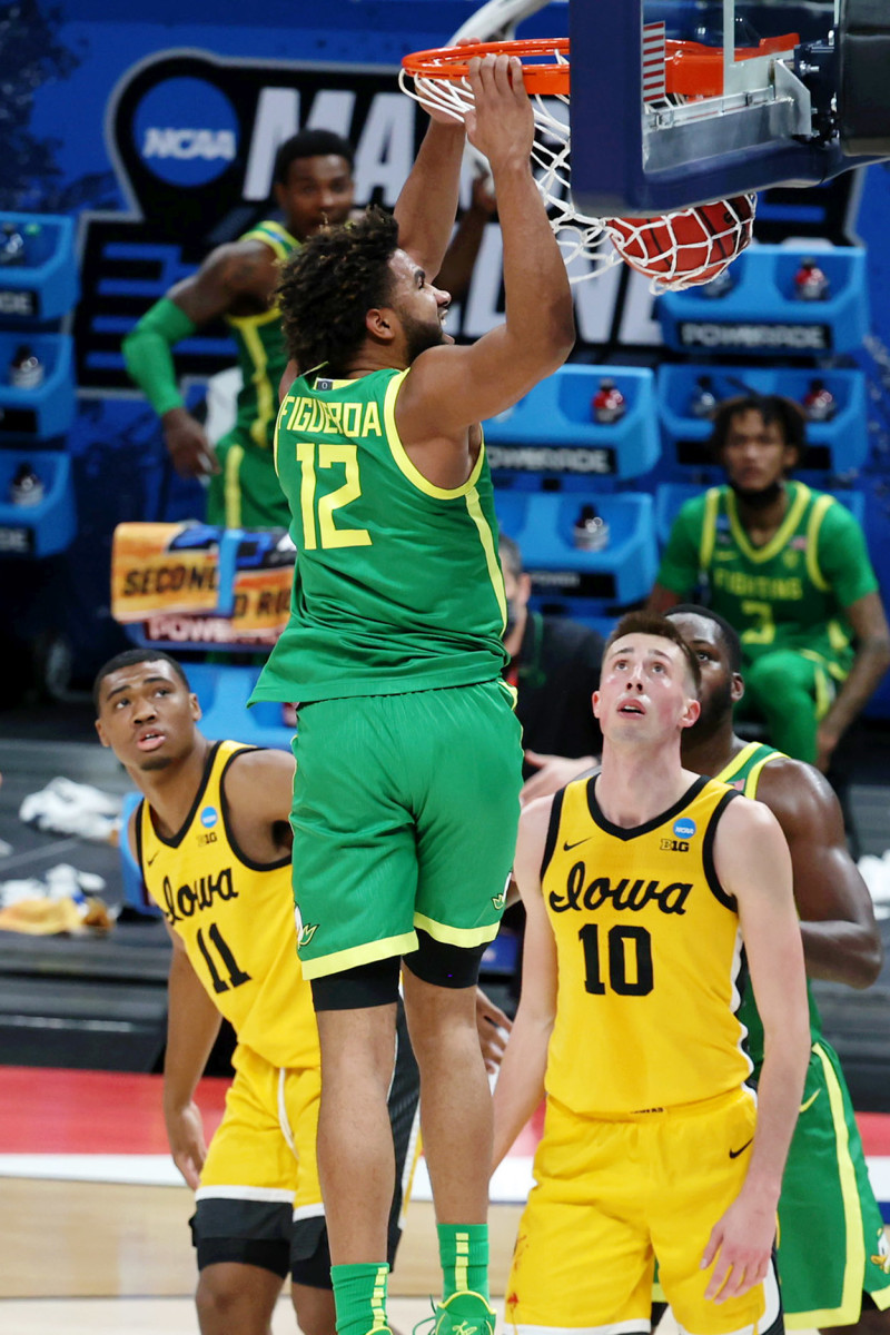 LJ Figueroa (12) throws down a dunk in the NCAA Tournament while Iowa's Joe Wieskamp (10) and Tony Perkins (11) look on. 