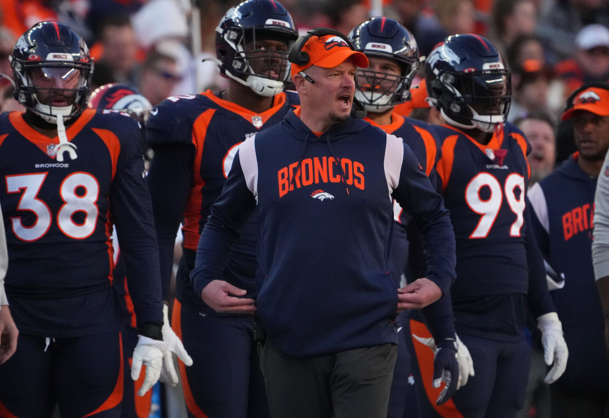 Former Denver Broncos head coach Nathaniel Hackett walks along the sidelines with players behind him, shouting