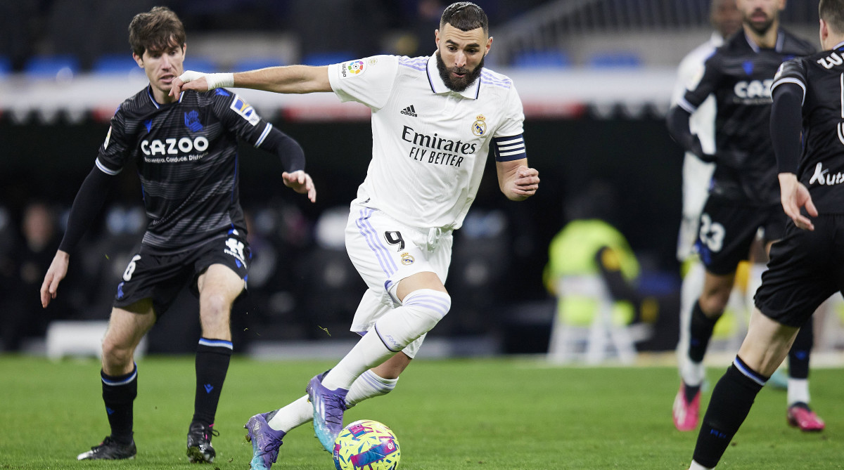 Real Madrid striker Karim Benzema dribbles around Real Sociedad defenders.