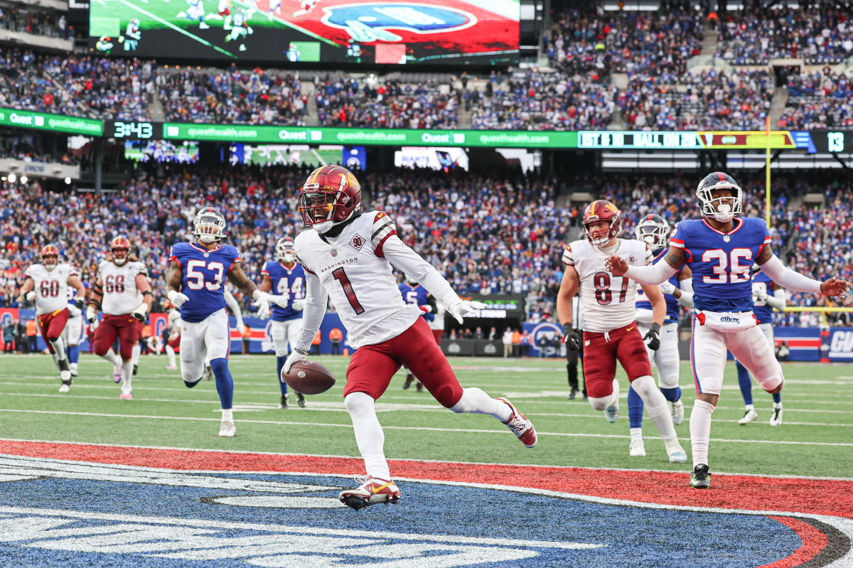 Jahan Dotson runs into the endzone with the ball in one hand, his arms spread to each side