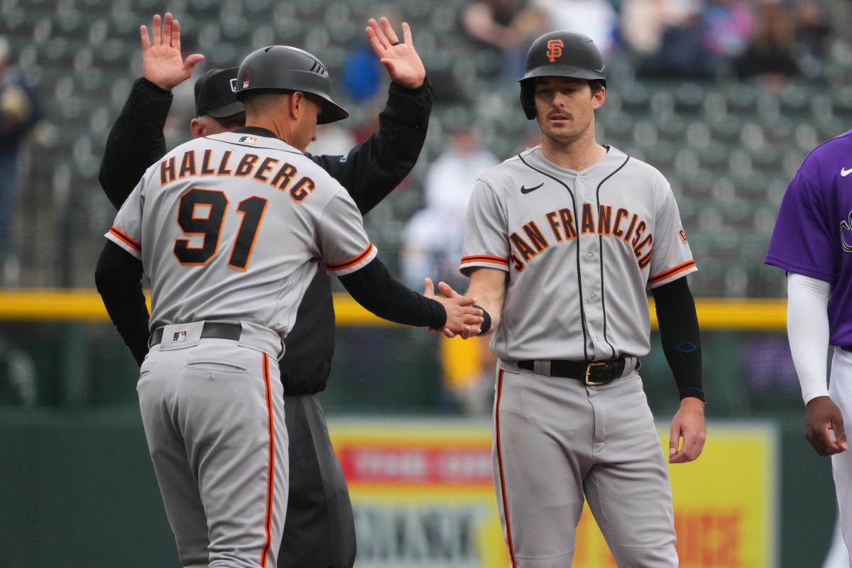 SF Giants outfielder Mike Yastrzemski high-fives third-base coach Mark Hallberg during their game against the Rockies on September 22, 2022.