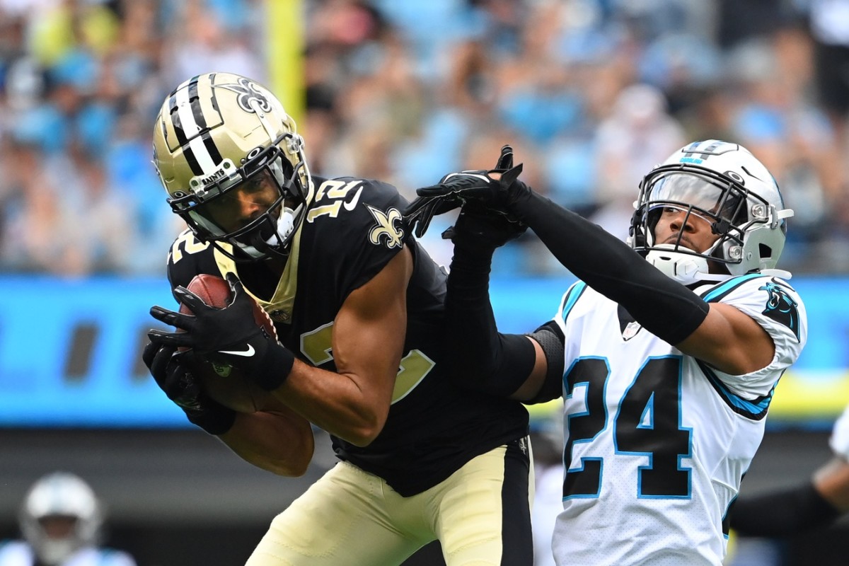 New Orleans Saints wide receiver Chris Olave (12) catches the ball as Carolina Panthers cornerback CJ Henderson (24) defends. Mandatory Credit: Bob Donnan-USA TODAY Sports