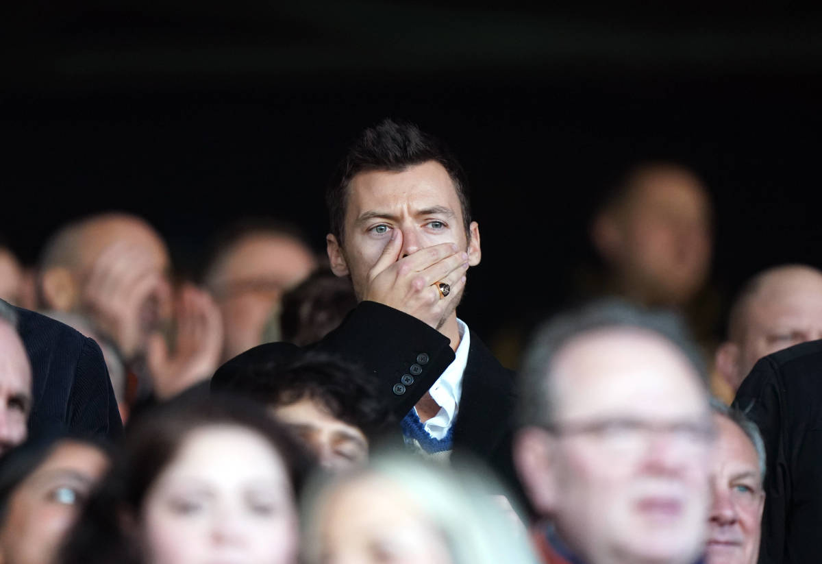 Harry Styles pictured covering his mouth with his hand while watching the Premier League game between Luton Town and Manchester United at Kenilworth Road in February 2024