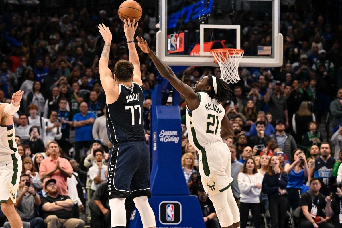 Luka Doncic shoots a 3-pointer over the outstretched arm of Jrue Holiday.