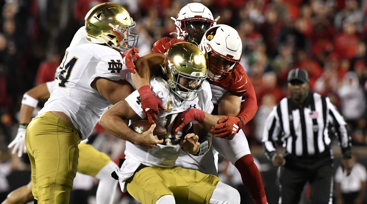 Louisville defensive lineman Ashton Gillotte, center right, sacks Notre Dame quarterback Sam Hartman