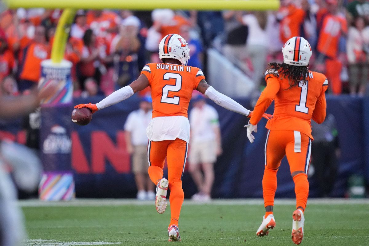 Patrick Surtain II runs with the ball in one hand and his arms out