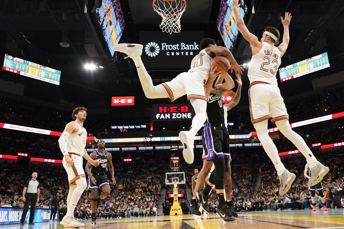 Nov 17, 2023; San Antonio, Texas, USA; Sacramento Kings center Domantas Sabonis (10) gets crushed by San Antonio Spurs forward Julian Champagnie (30) and center Zach Collins (23) during the second half at Frost Bank Center.