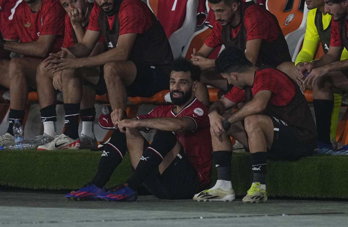 Egypt captain Mo Salah pictured (center) sat on the ground by his team's bench after being subbed off with an injury during a 2-2 draw against Ghana at the Africa Cup of Nations in January 2024